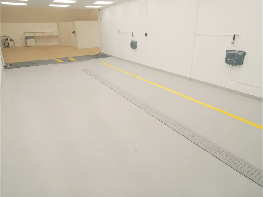 Solid grey epoxy floor with safety lines in a commercial bay